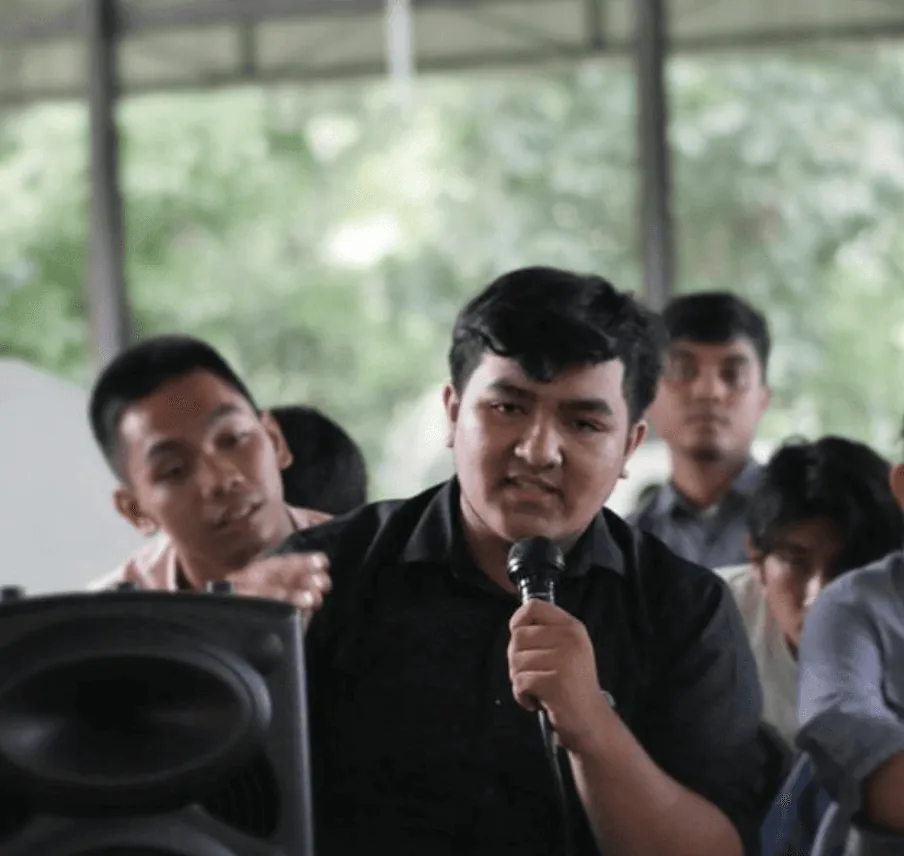 Benni speaking into a microphone at a community event